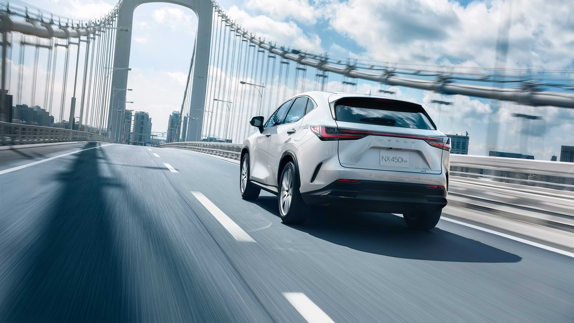 Rear view of the 2021 NX 450h+ driving across a cable bridge.