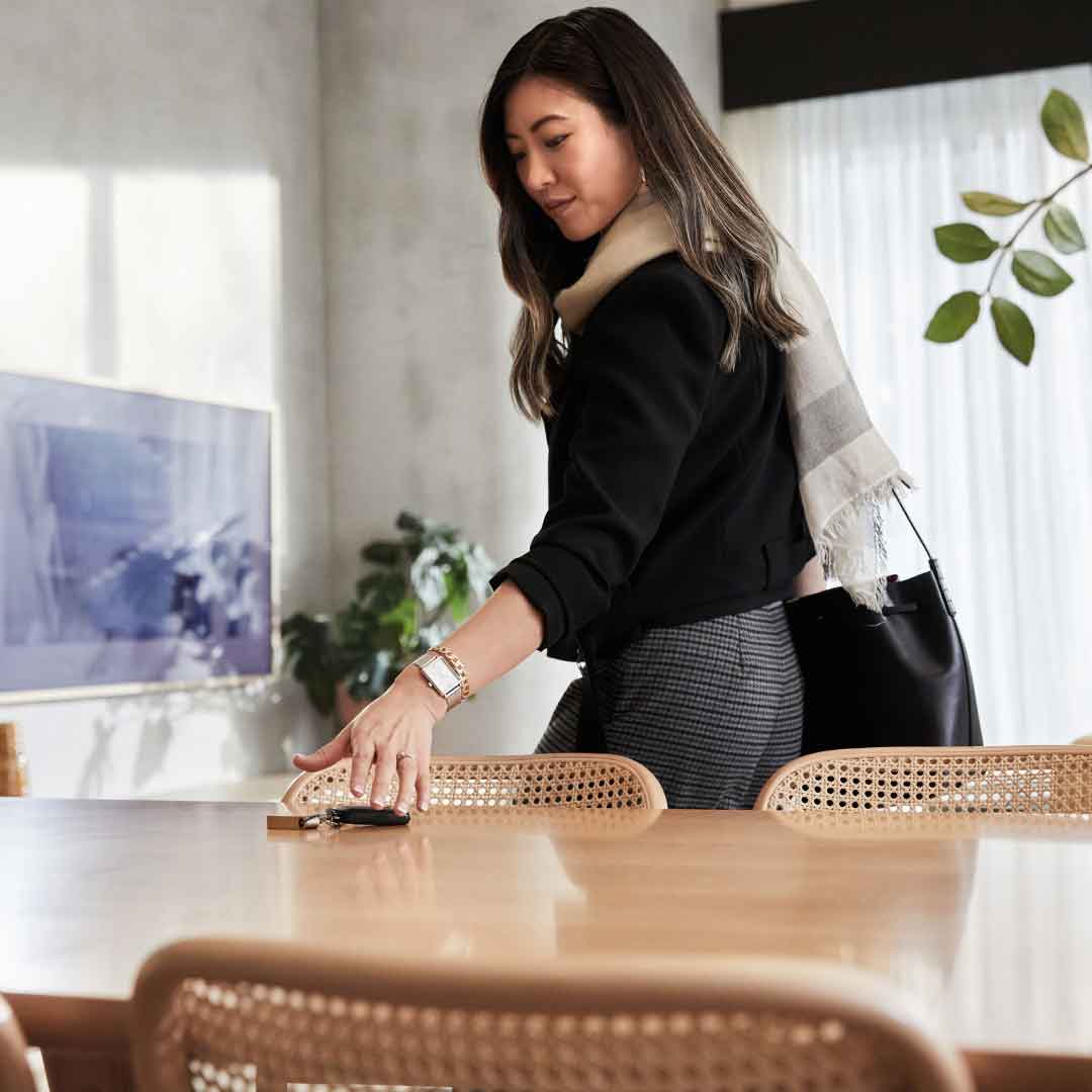 A lady picks up car keys off a kitchen table.
